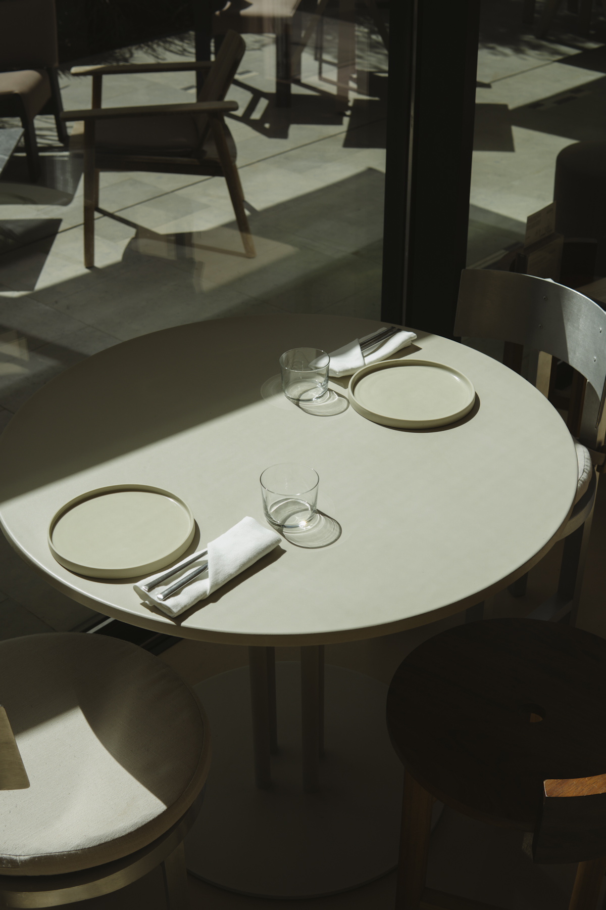 A laid table in hard afternoon light beside a slatted timber screen