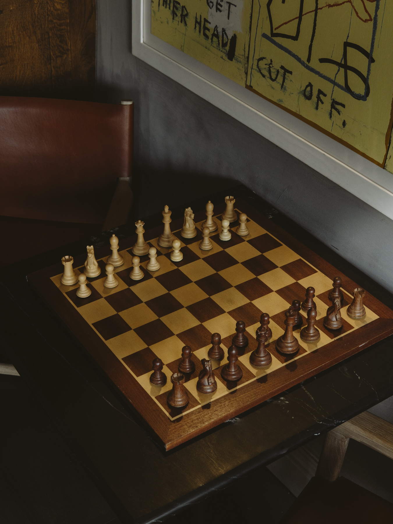 A chess board set for a new game on a dark timber table