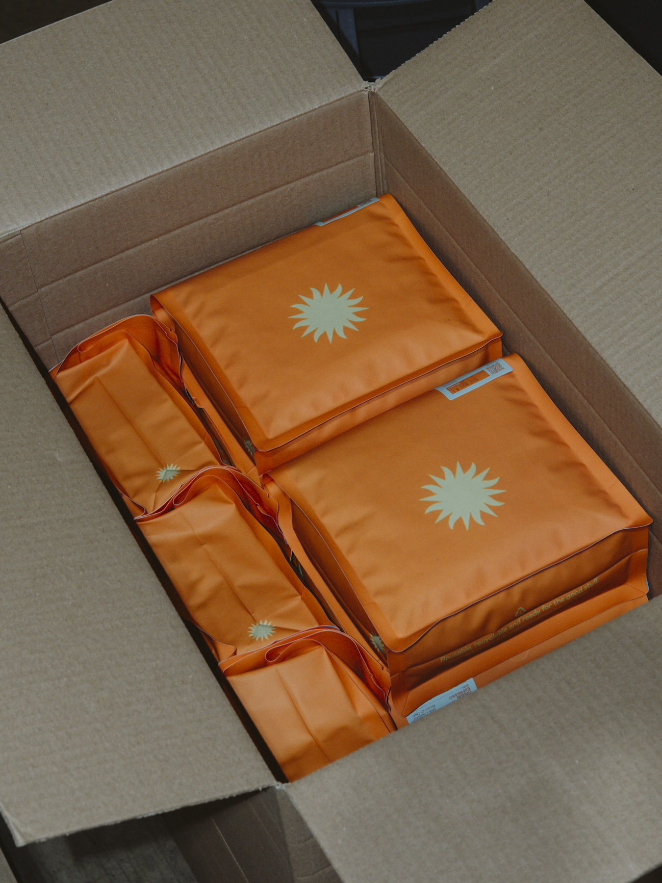 A cardboard box packed with orange bags of coffee