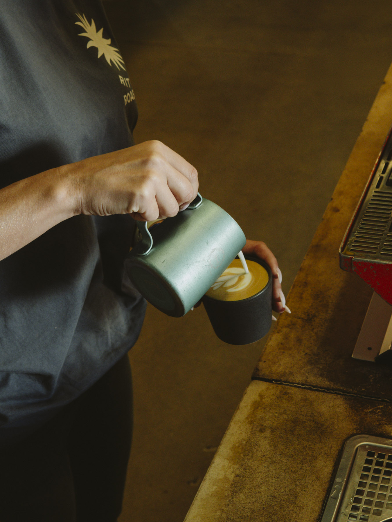 A barista pouring milk into a flat white